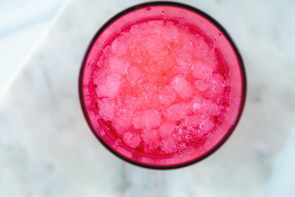 Overhead view of a pink shaker filled with ice and vodka lemonade ingredients.