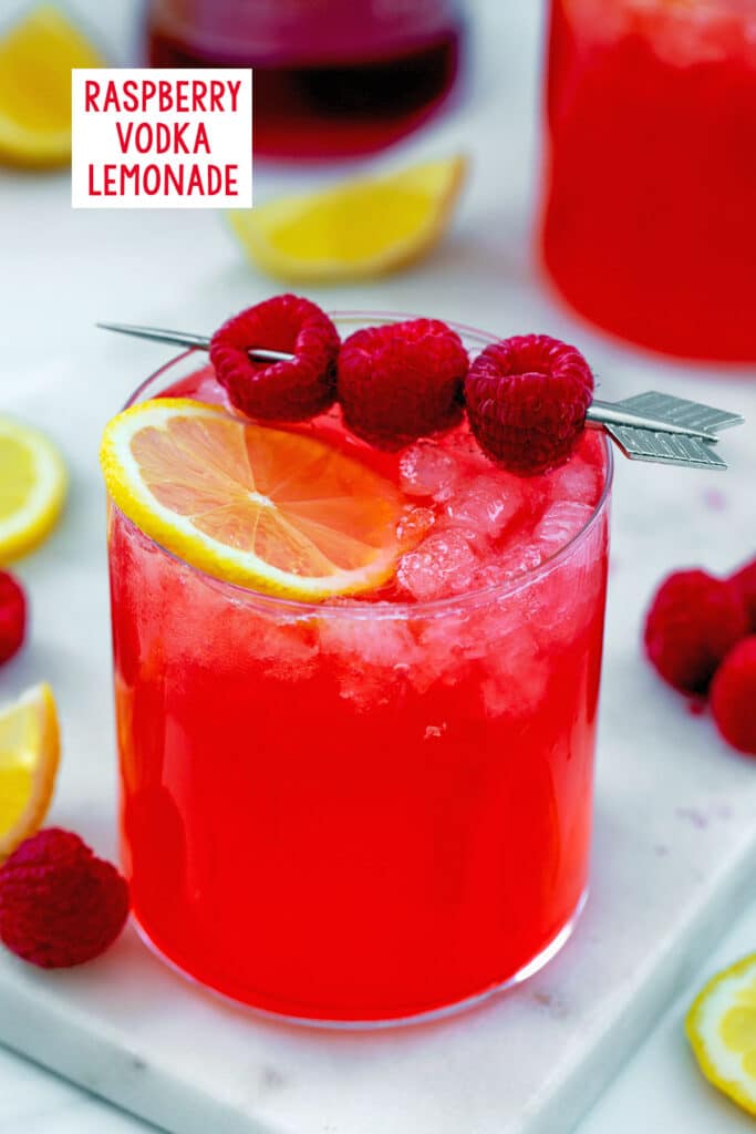 Overhead view of raspberry vodka lemonade in a glass with lemon slice and cocktail pick with fresh raspberries with recipe title at top.