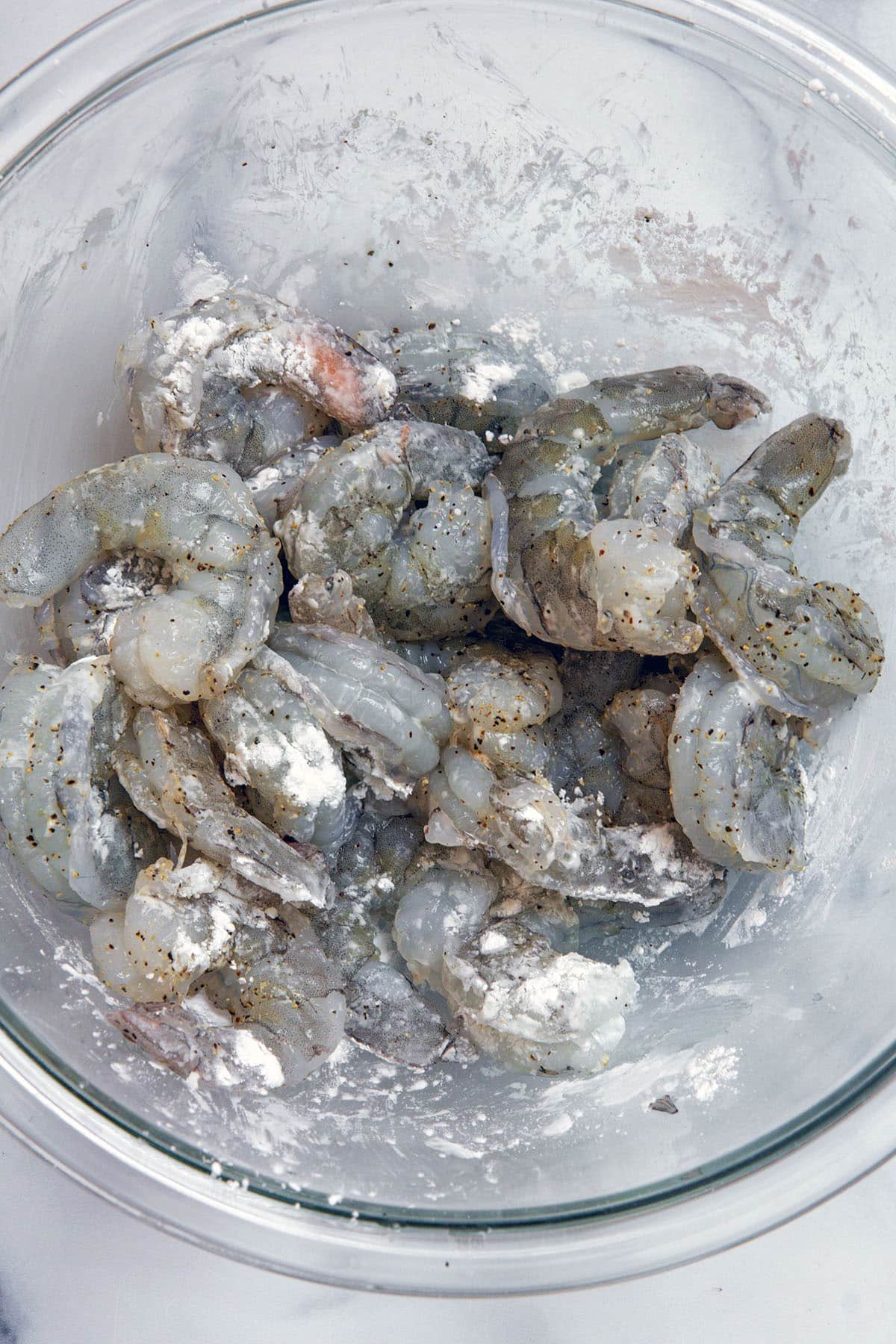 Raw shrimp in bowl with cornstarch.