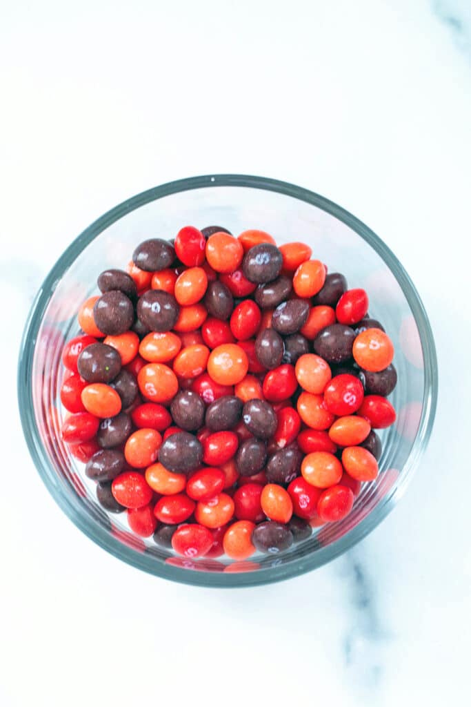 Pink, red, and purple Skittles in a bowl.
