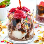 Closeup view of a red wine affogato with strawberries, chocolate sauce, and sprinkles.