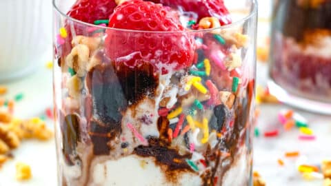 Closeup view of a red wine affogato with strawberries, chocolate sauce, and sprinkles.