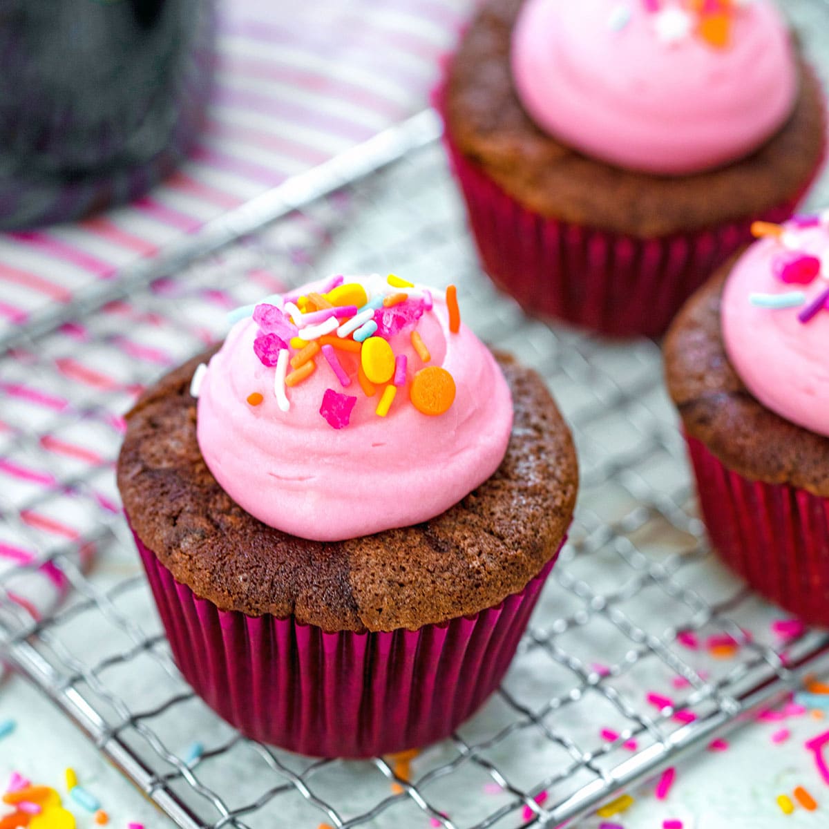 Closeup view of a chocolate red wine cupcake with pink frosting and sprinkles.