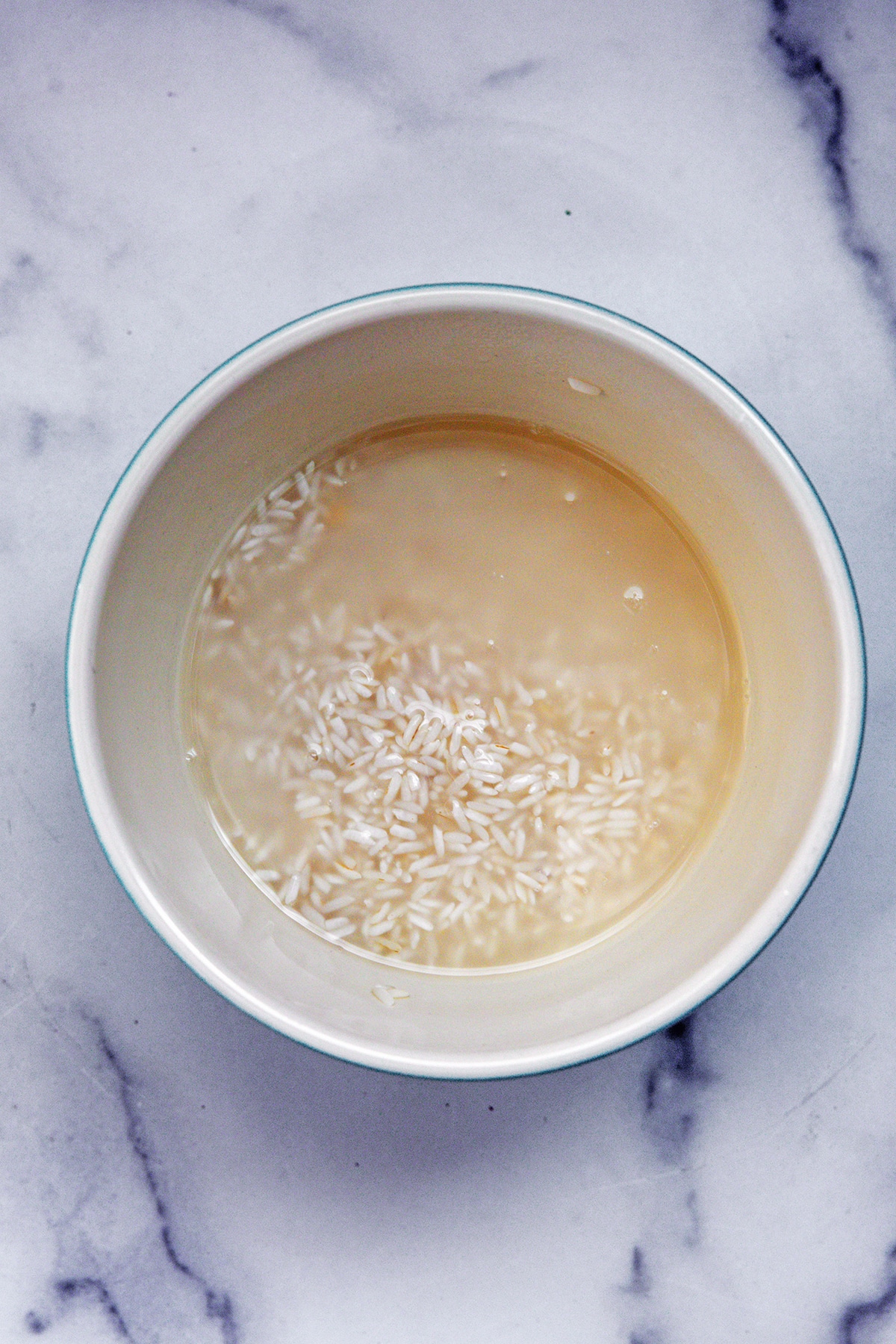 White rice soaking in water in bowl.