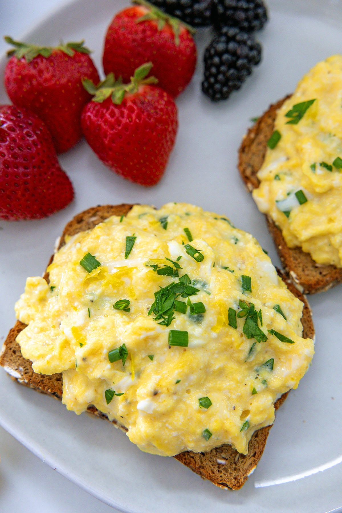 Closeup view of a piece of taste with ricotta scrambled eggs on top.