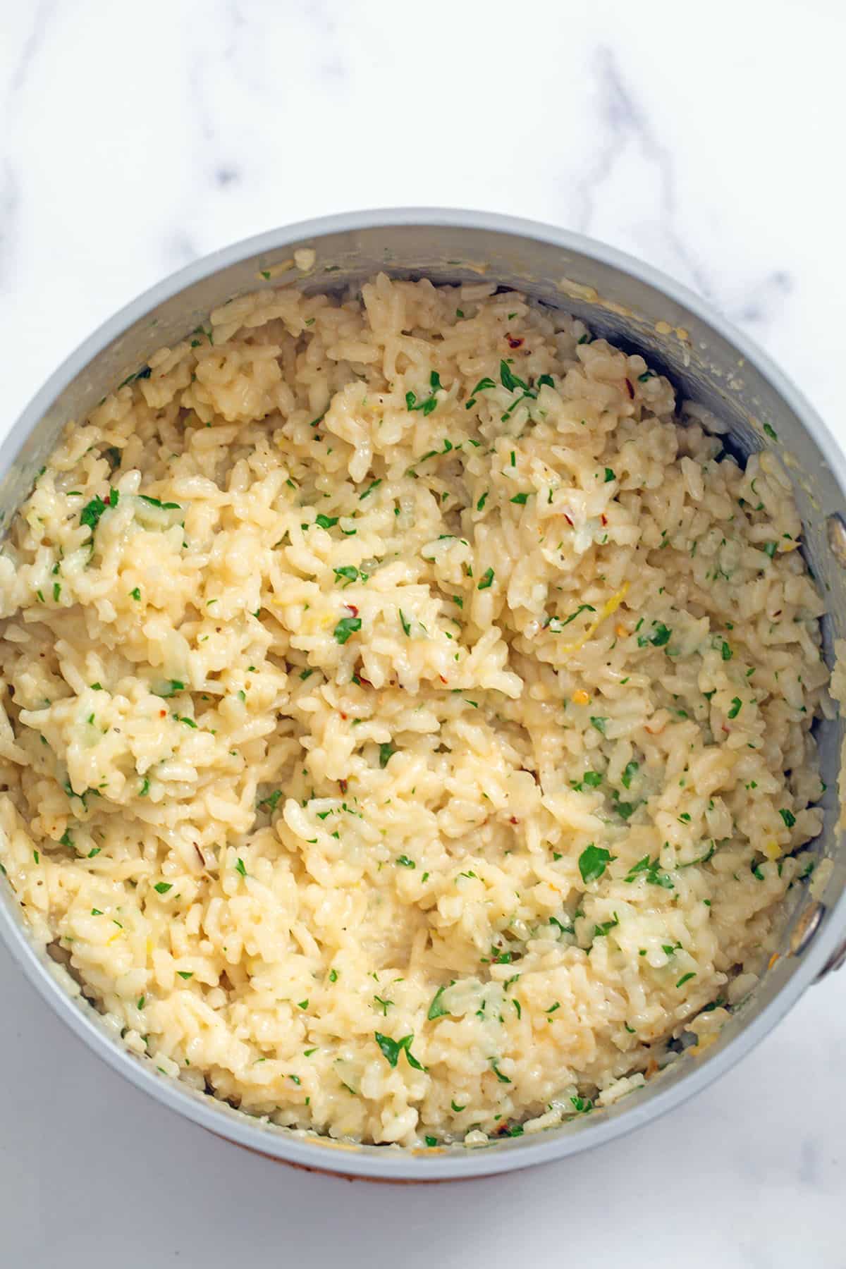 Risotto in saucepan with parsley, parmesan, and seasoning mixed in.