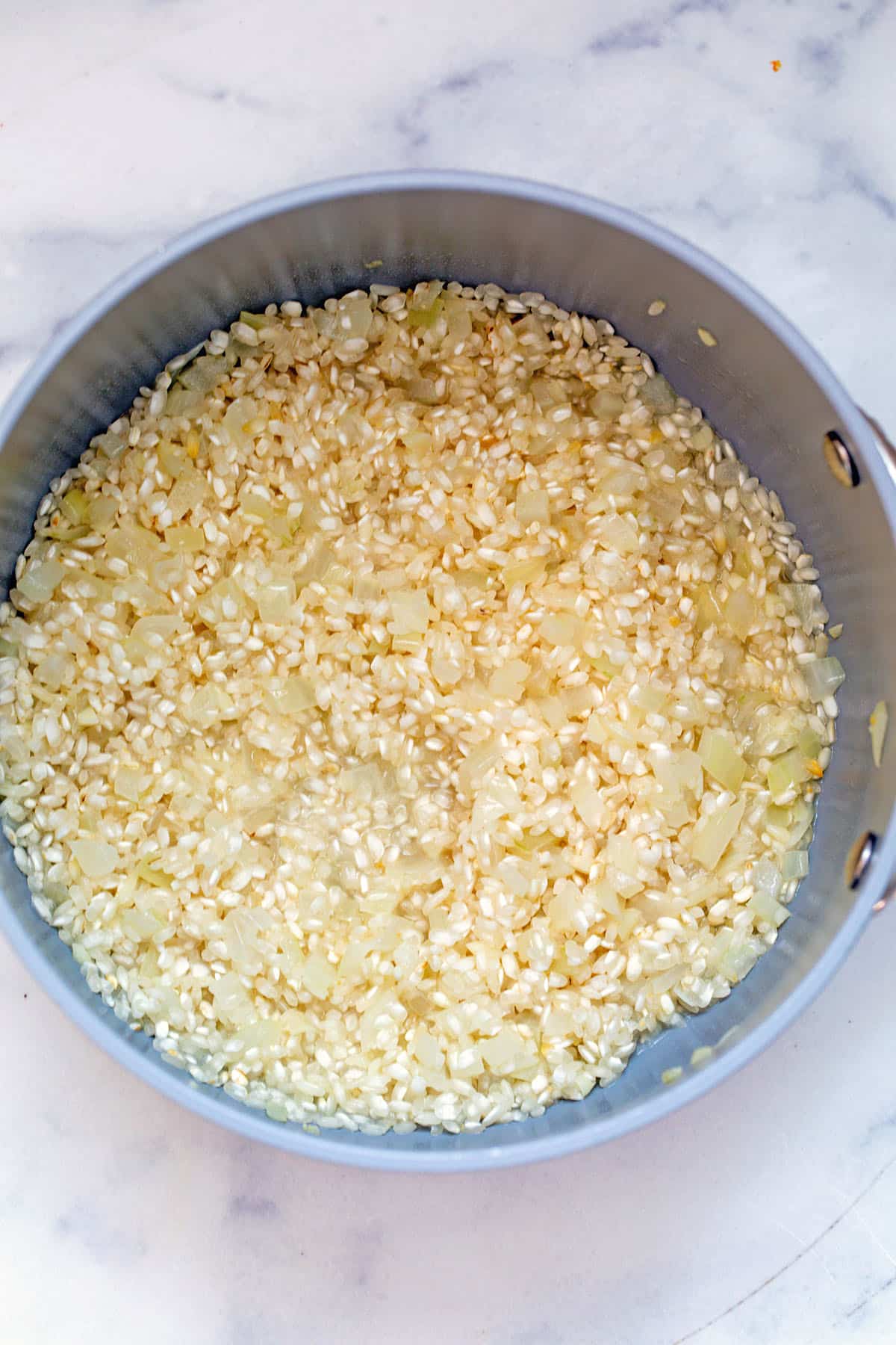 Risotto and onion in saucepan.