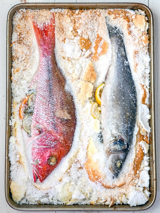 Salt baked fish encased in salt on baking sheet.