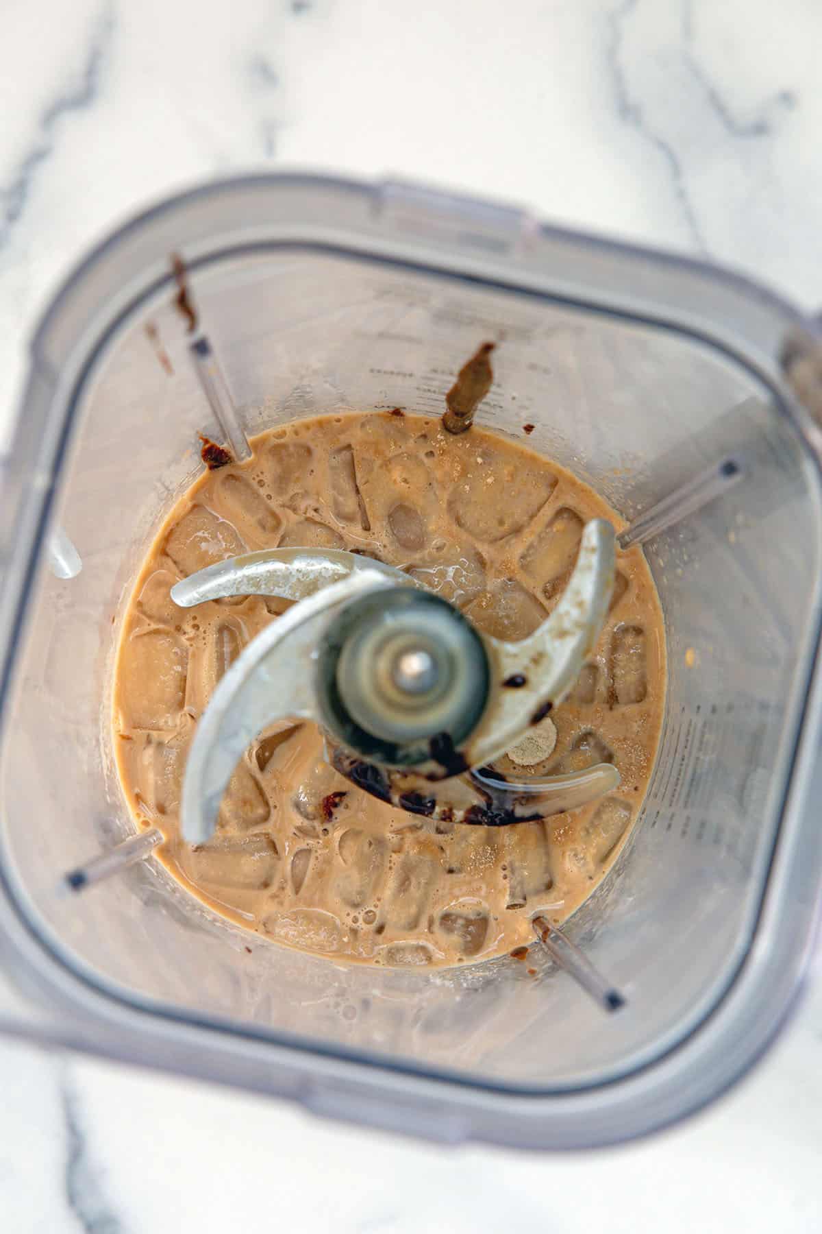 Overhead view of ice, milk, and mocha sauce in a blender.