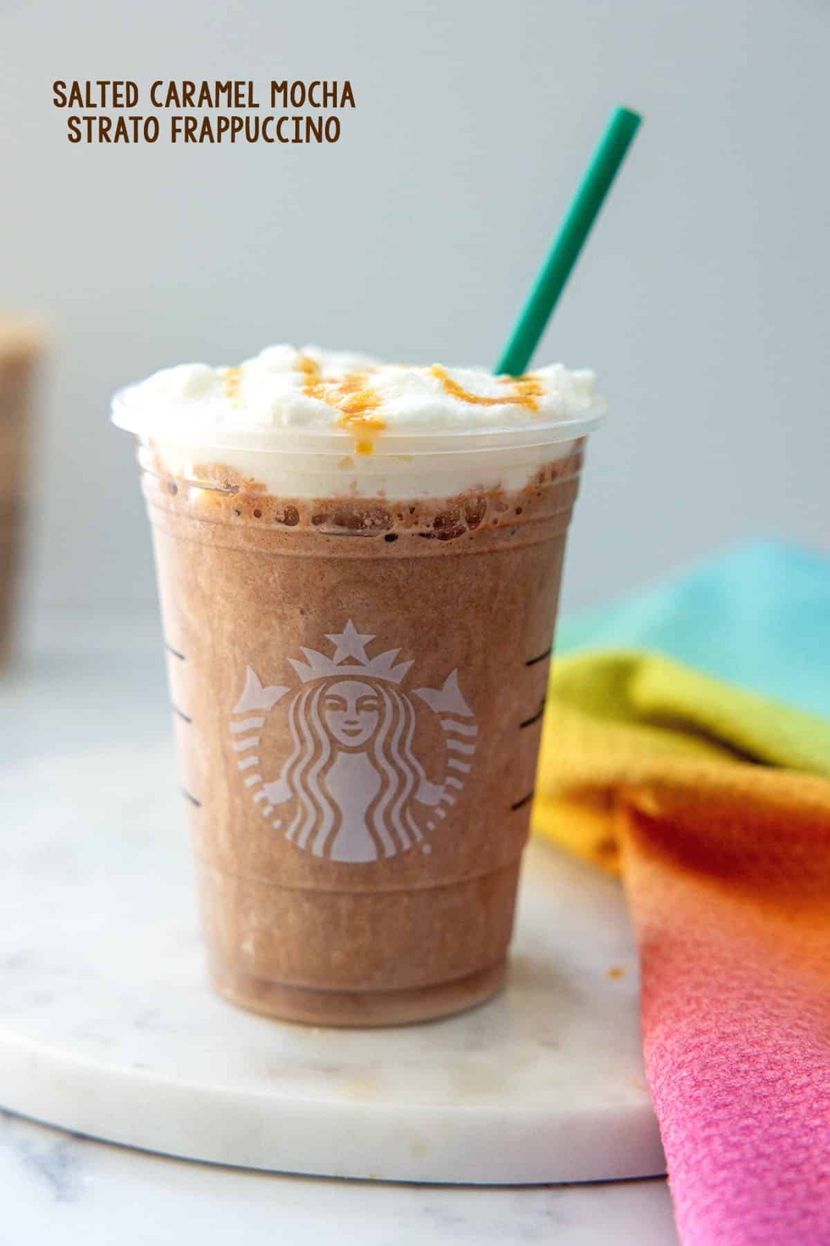 Head-on view of a Salted Caramel Mocha Strato Frappuccino with cold foam and green straw with recipe title at top.