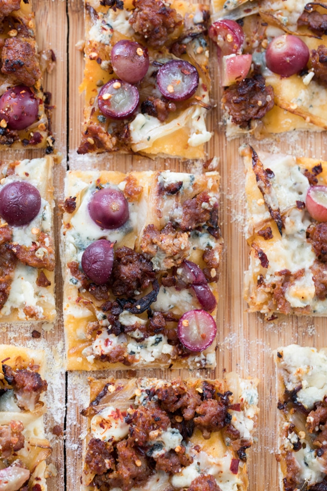 A shot from above showing a few square slices of sausage, grape, and gorgonzola flatbread pizza
