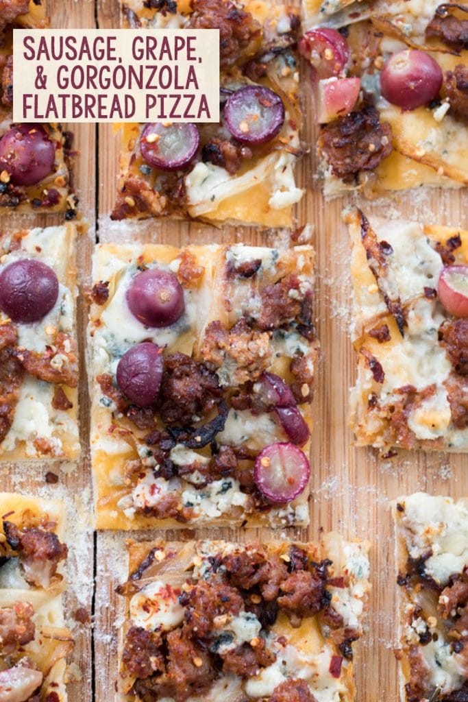 Thin crust flatbread pizza cut into squares and topped with sausage, grapes, onions, and gorgonzola cheese with text in the corner that says "Sausage, Grape, and Gorgonzola Flatbread"