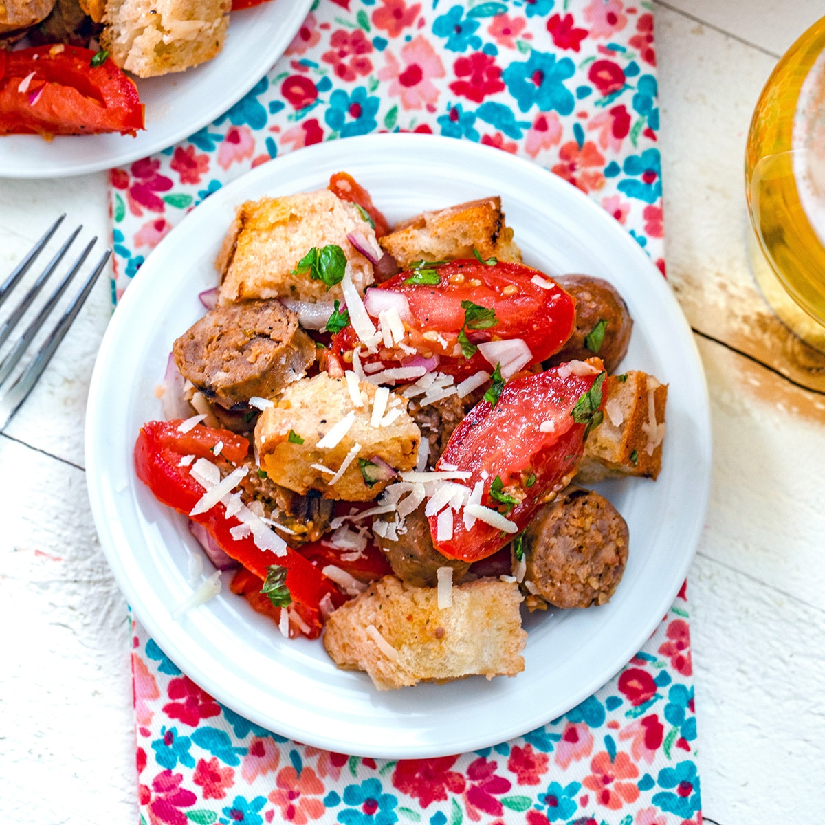 Closeup view of a sausage panzanella salad with bread, tomatoes, and sliced Italian sausages.
