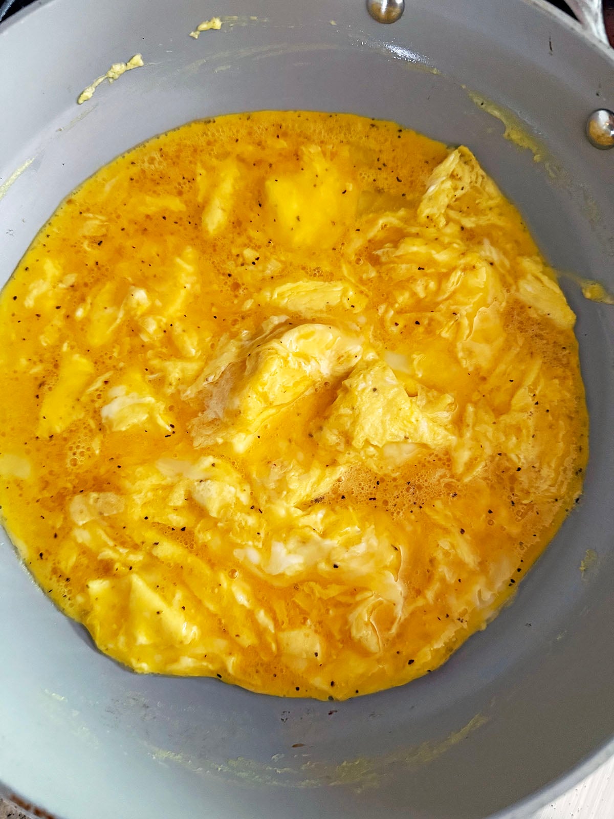Eggs being scrambled in skillet in brown butter.