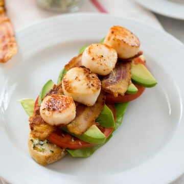 Closeup view of an open-faced seared scallop BLT sandwich.
