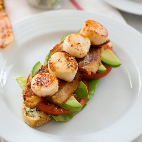 Closeup view of an open-faced seared scallop BLT sandwich.
