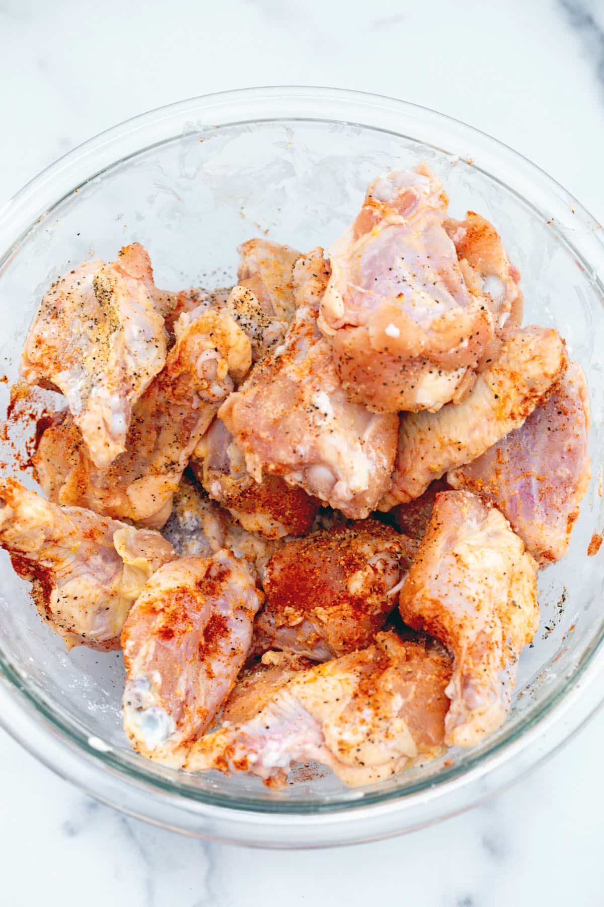 Chicken wings with seasoning in a bowl.
