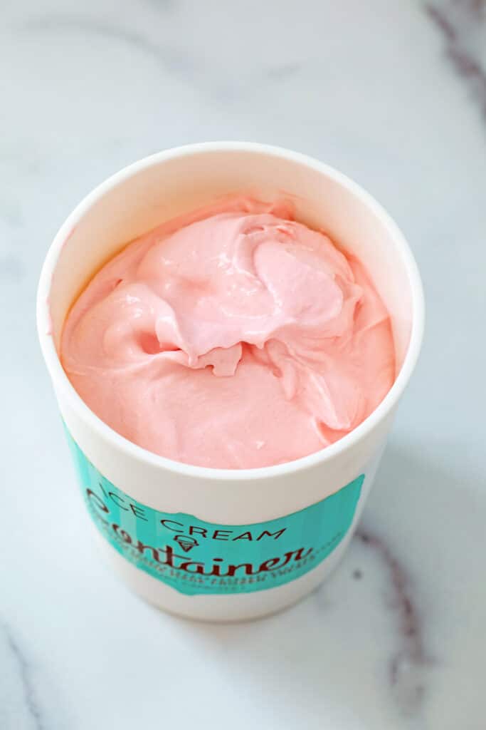 Pink Skittles ice cream in quart container.