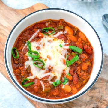 Overhead closeup view of chili topped with cheese in a bowl.
