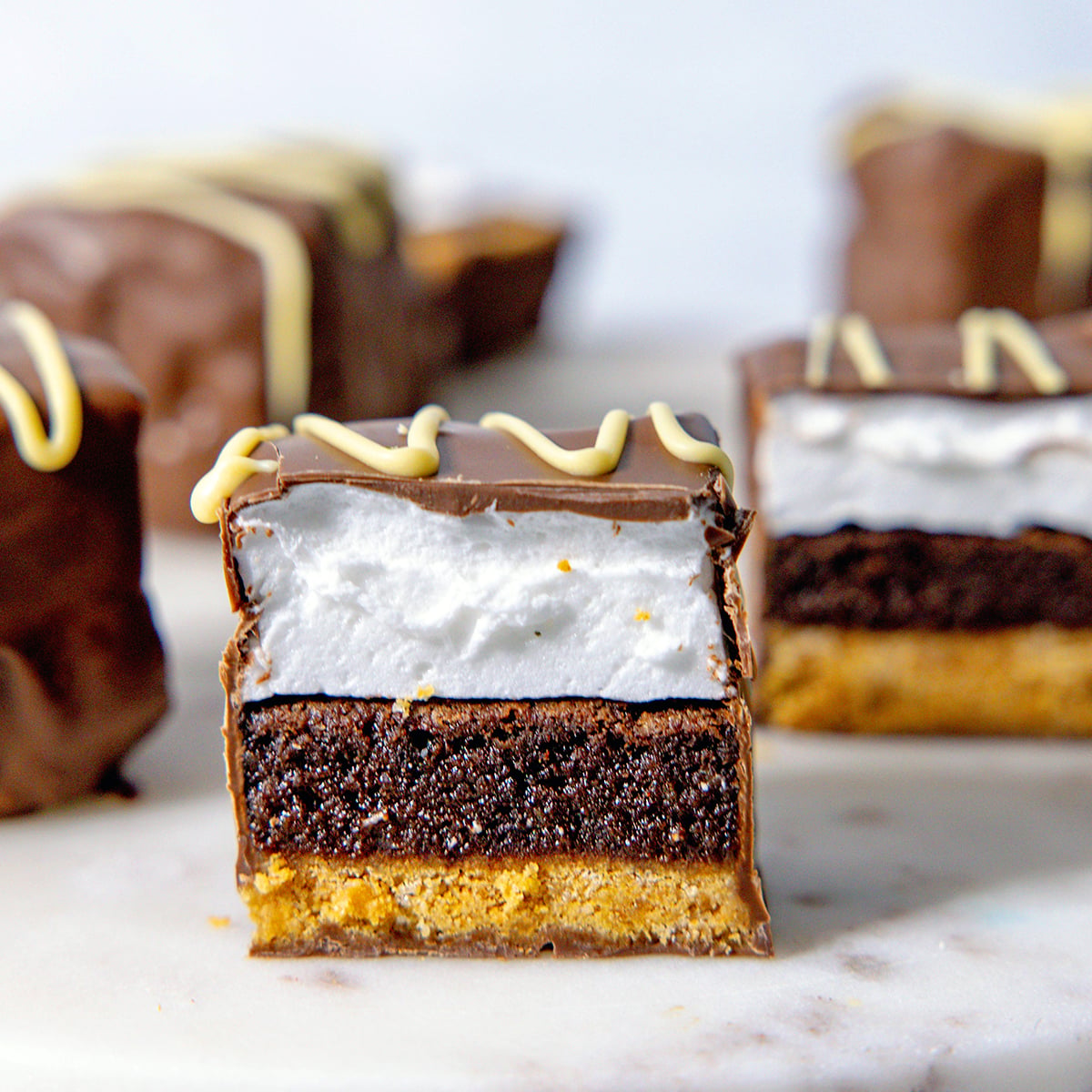 Close-up view of s'mores bars cut in half to show graham cracker, brownie, and marshmallow layers.