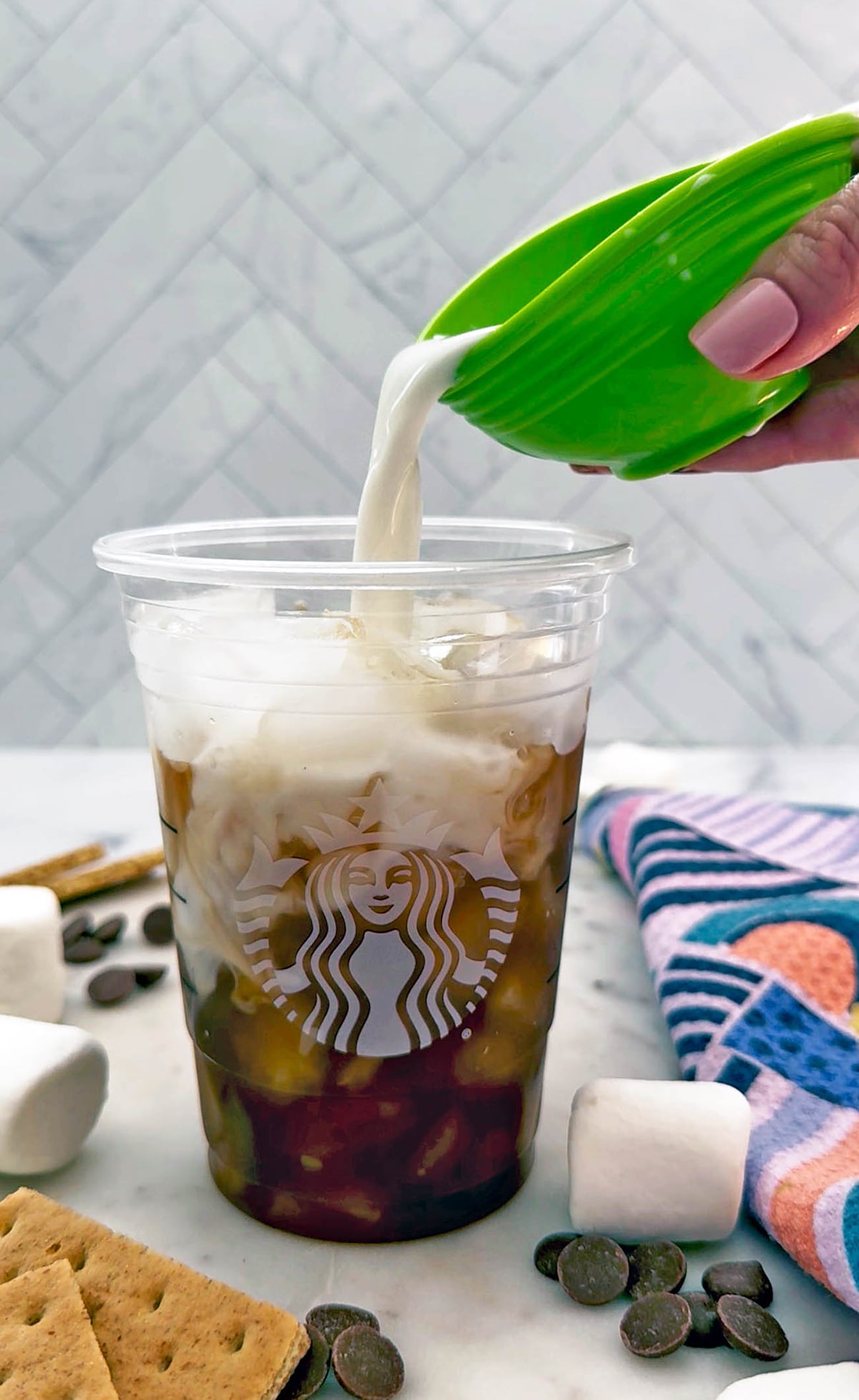 Iced chai with marshmallow syrup and milk being poured in.