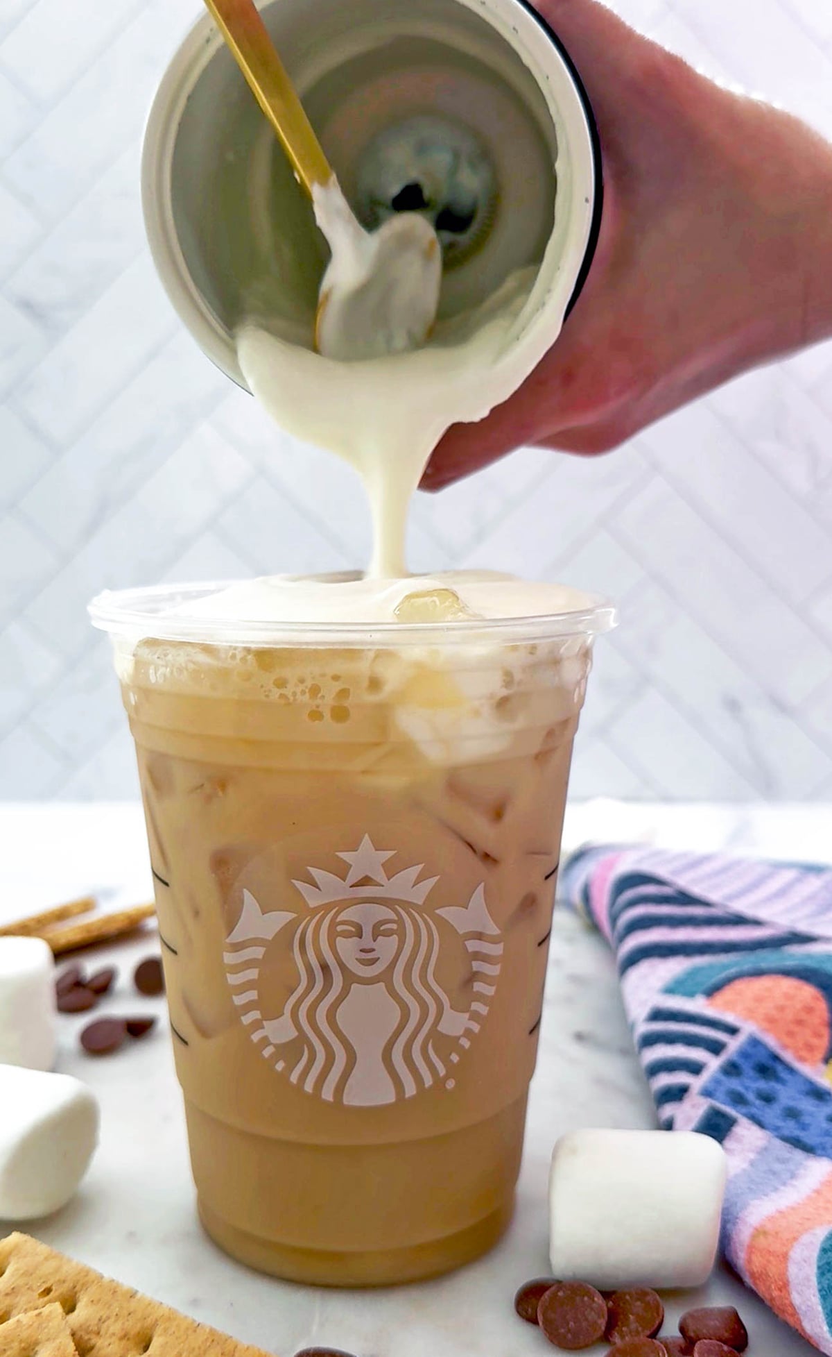 Iced S'mores Chai with marshmallow cold foam being poured on top.