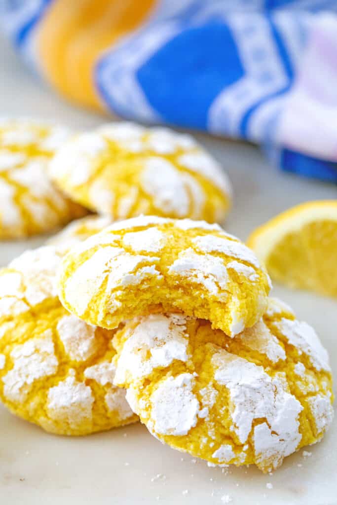 Soft lemon cookies with confectioners' sugar piled up with lemon wedge in background.
