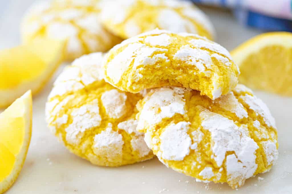 Landscape closeup view of a stack of soft lemon crinkle cookies with a bite taken out of the top cookie.