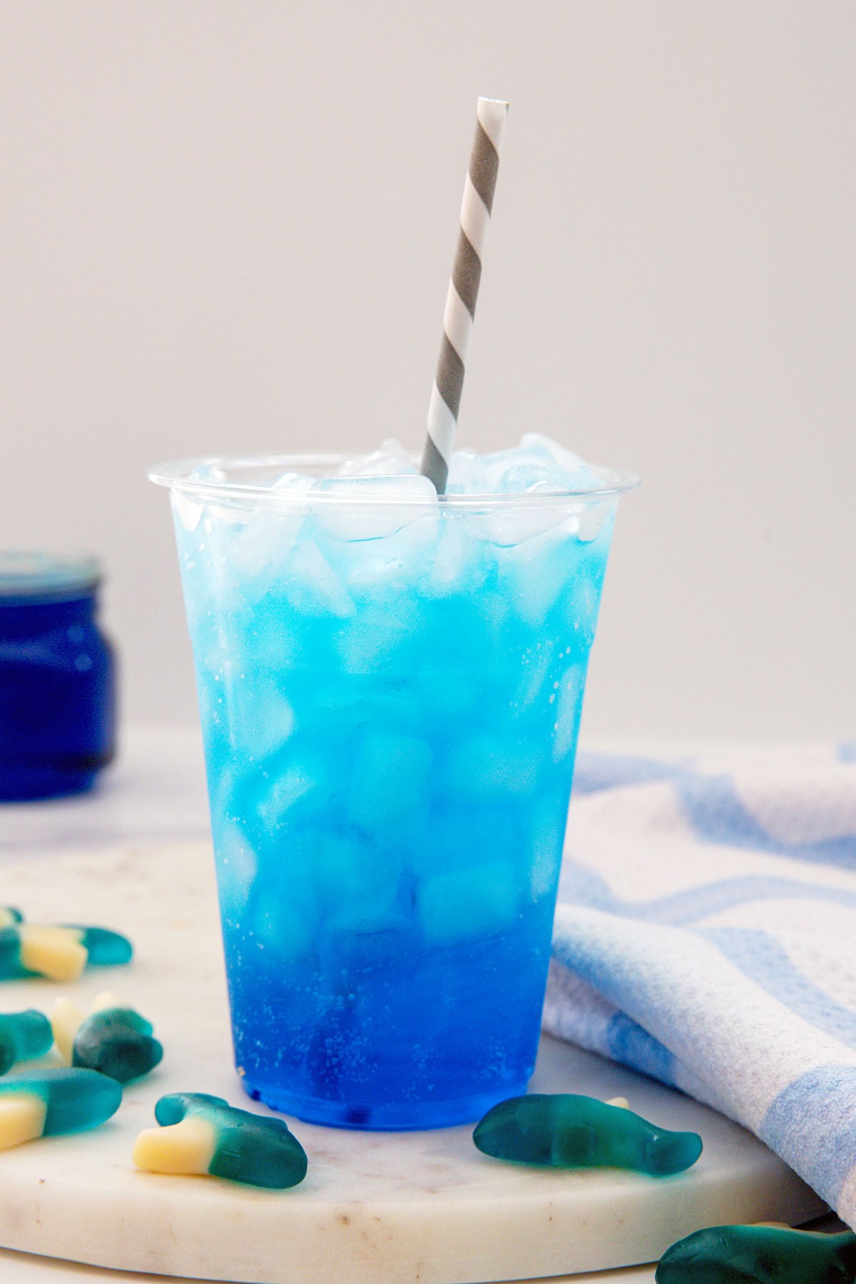 Head-on view of a blue Sonic Ocean Water drink with gummy sharks all around.