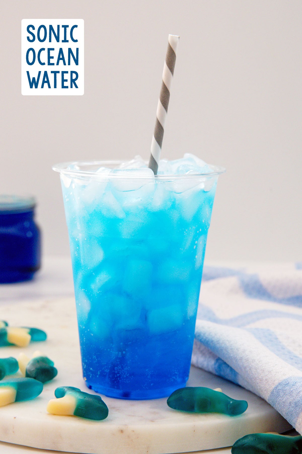Head-on view of a blue Sonic Ocean Water drink with gummy sharks all around and recipe title at top.