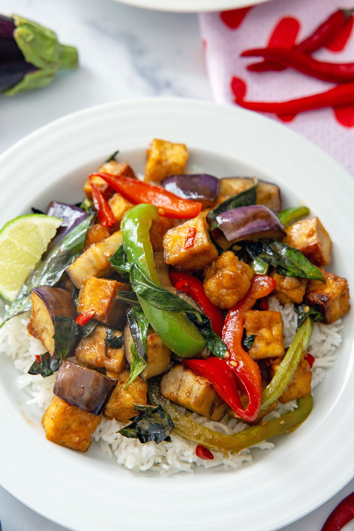Closeup view of spicy basil eggplant with tofu in white bowl.