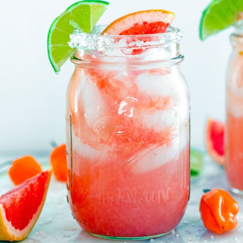 Head-on closeup of a spicy grapefruit margarita in a mason jar with salted rim and grapefruit and lime slices.