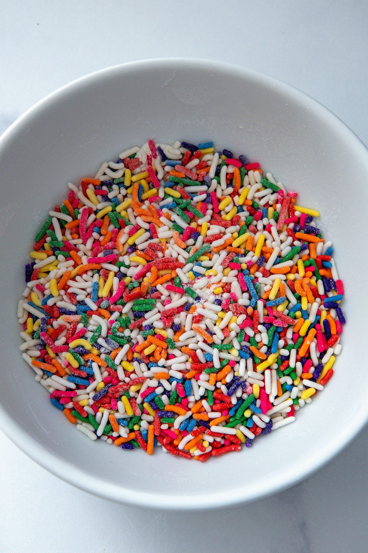 Rainbow sprinkles mixed with flour in small bowl.