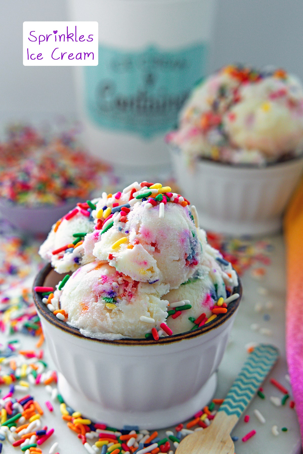 Head-on view of a bowl of sprinkles ice cream with second bowl of background, rainbow sprinkles all around, and recipe title at top.