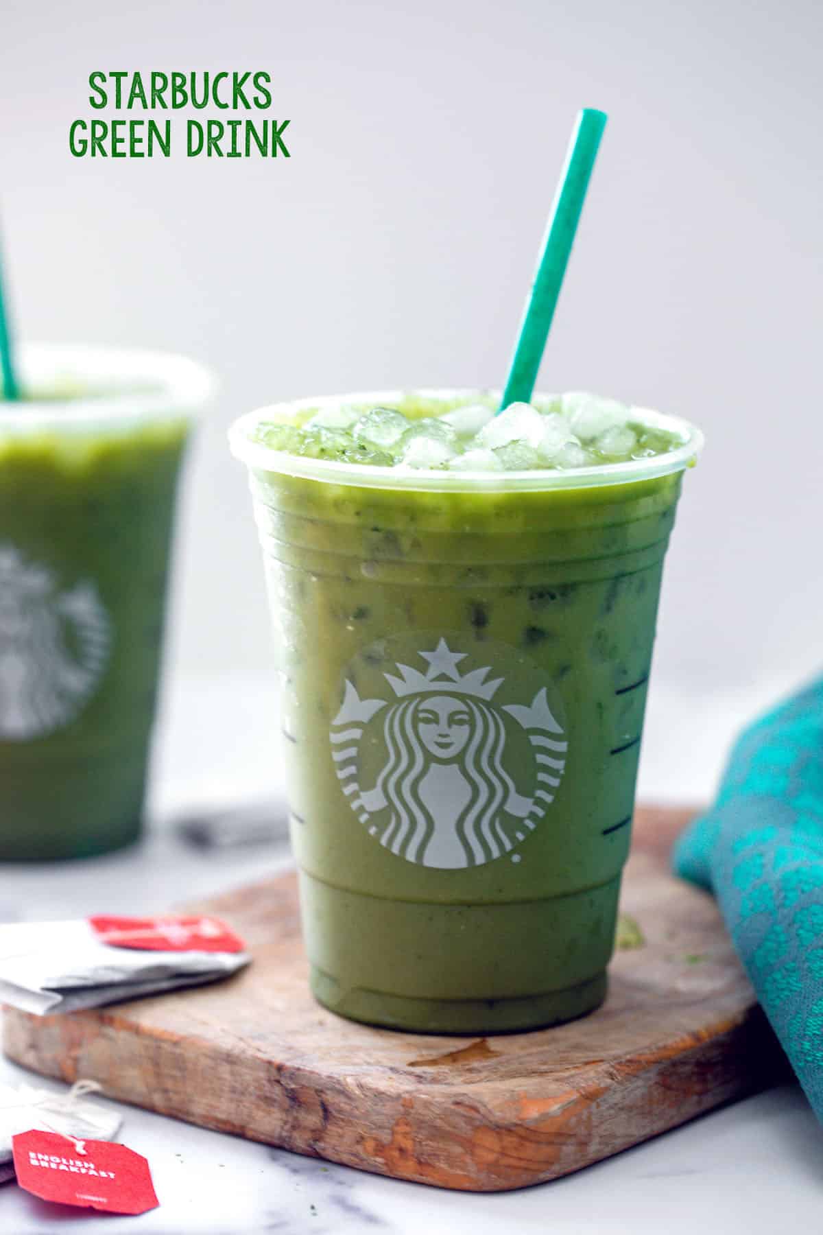 Head-on view of a Starbucks cup filled with Green Drink with black tea bags around the cup and the recipe title at top of image.
