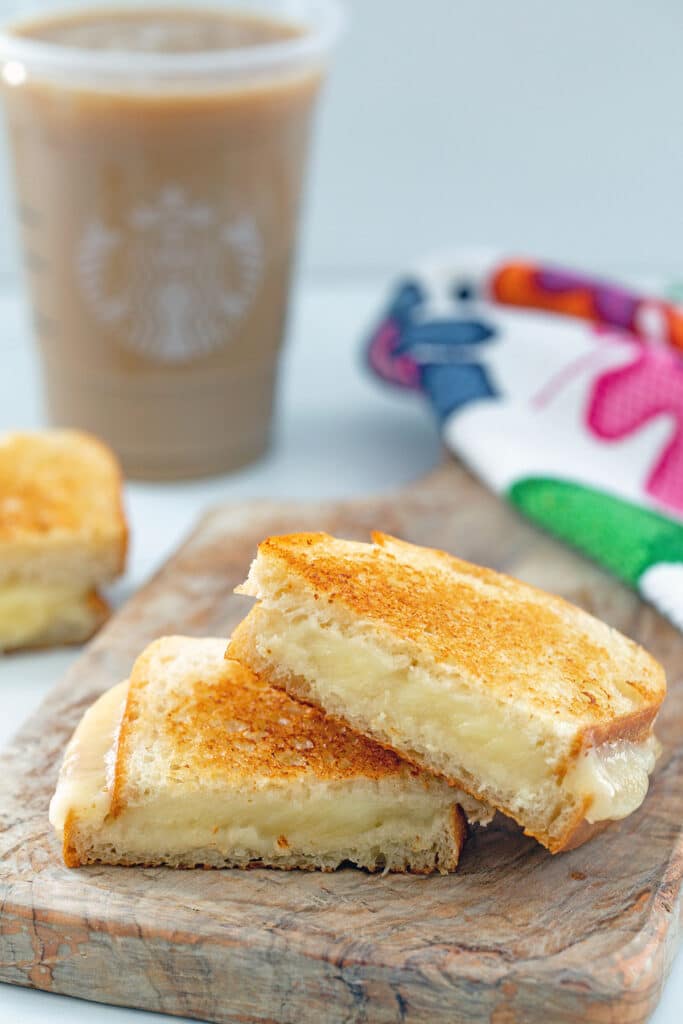Two halves of a grilled cheese sandwich stacked on each other with Starbucks iced coffee in background.