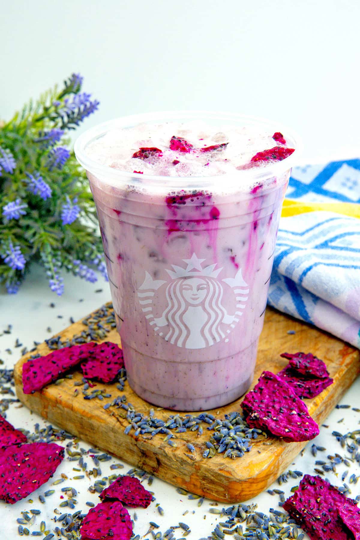 Overhead view of a Lavender Oatmilk Chill with freeze-dried dragonfruit pieces all around and lavender flowers in background.