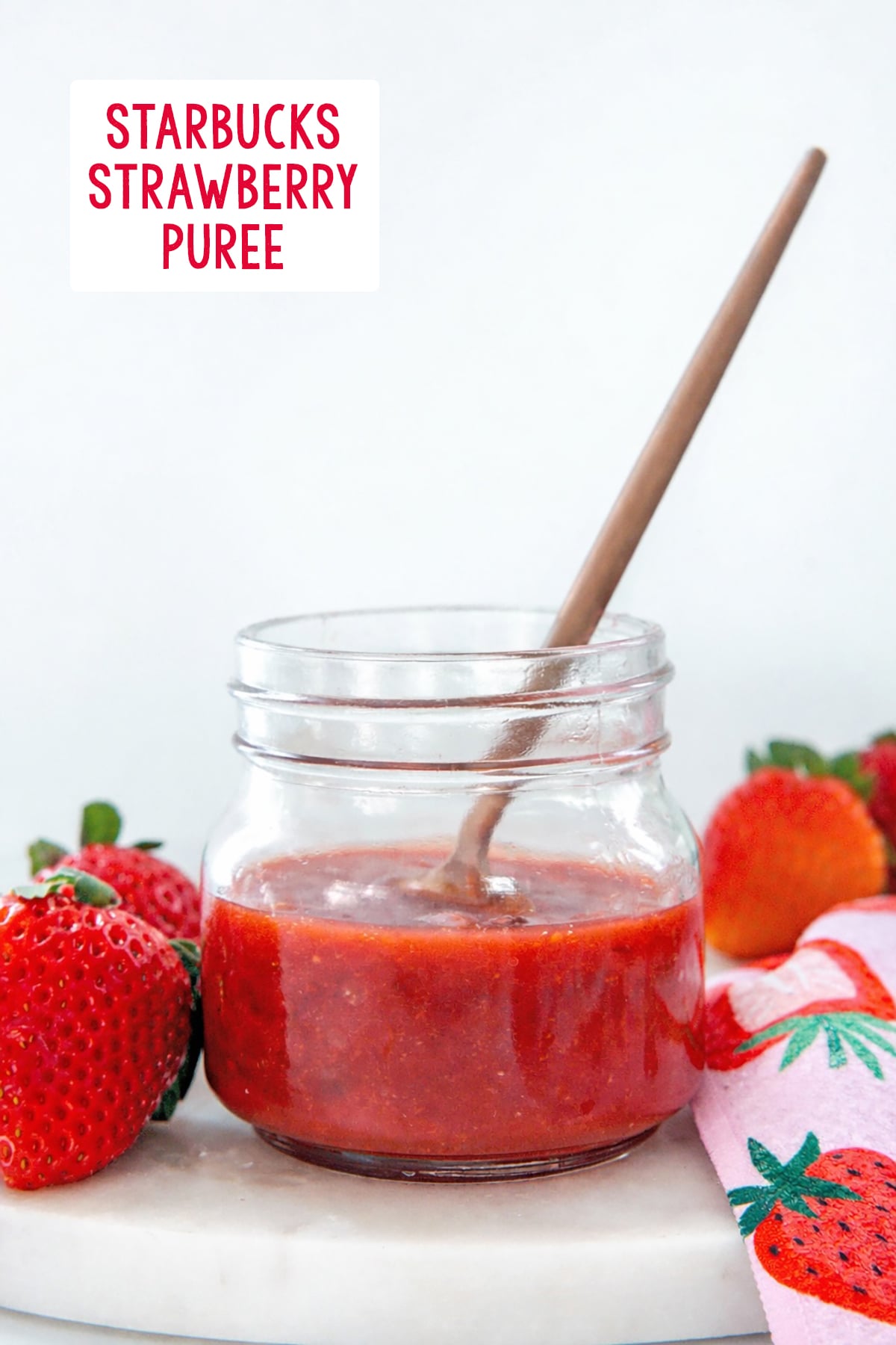 Head-on view of a small jar with homemade Starbucks strawberry puree in it with recipe title at top.