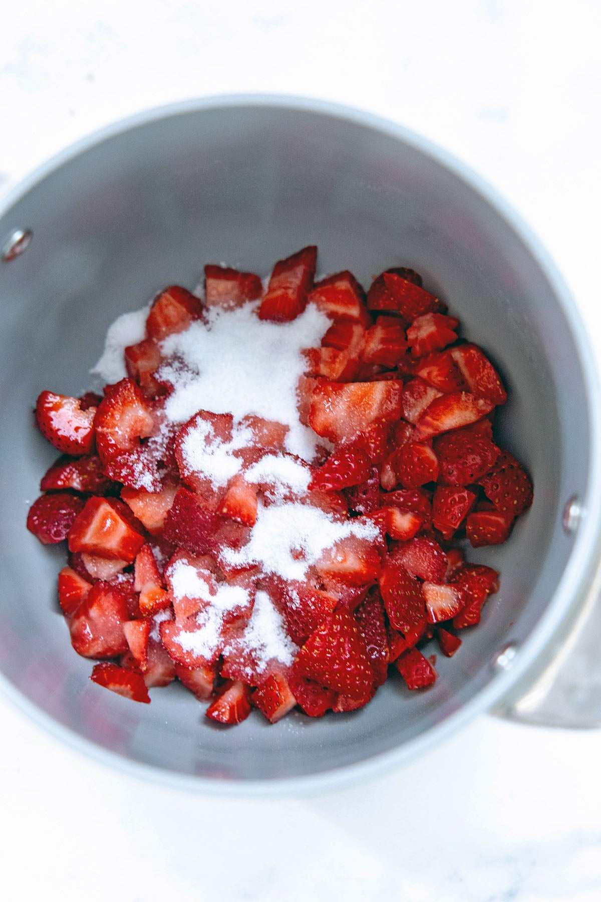 Chopped strawberries and sugar in saucepan.