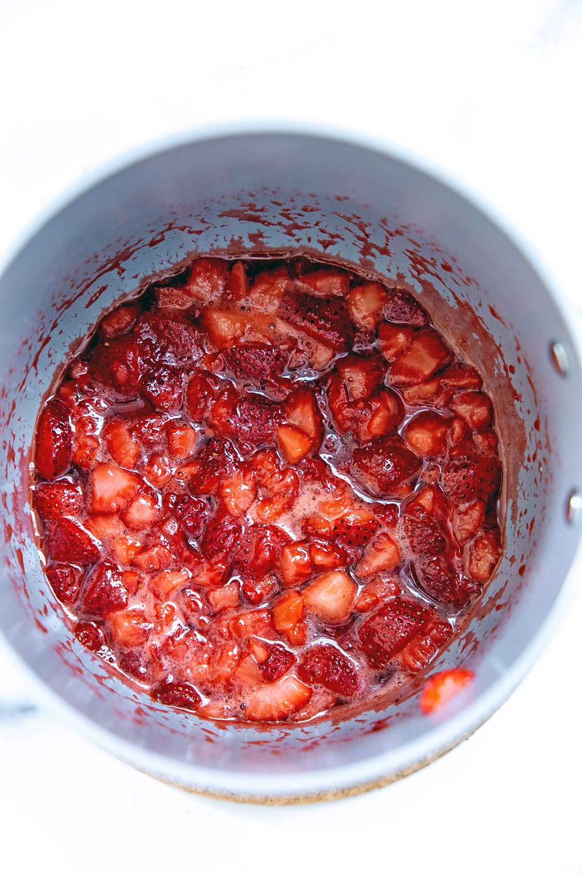 Chopped strawberries cooking in saucepan.