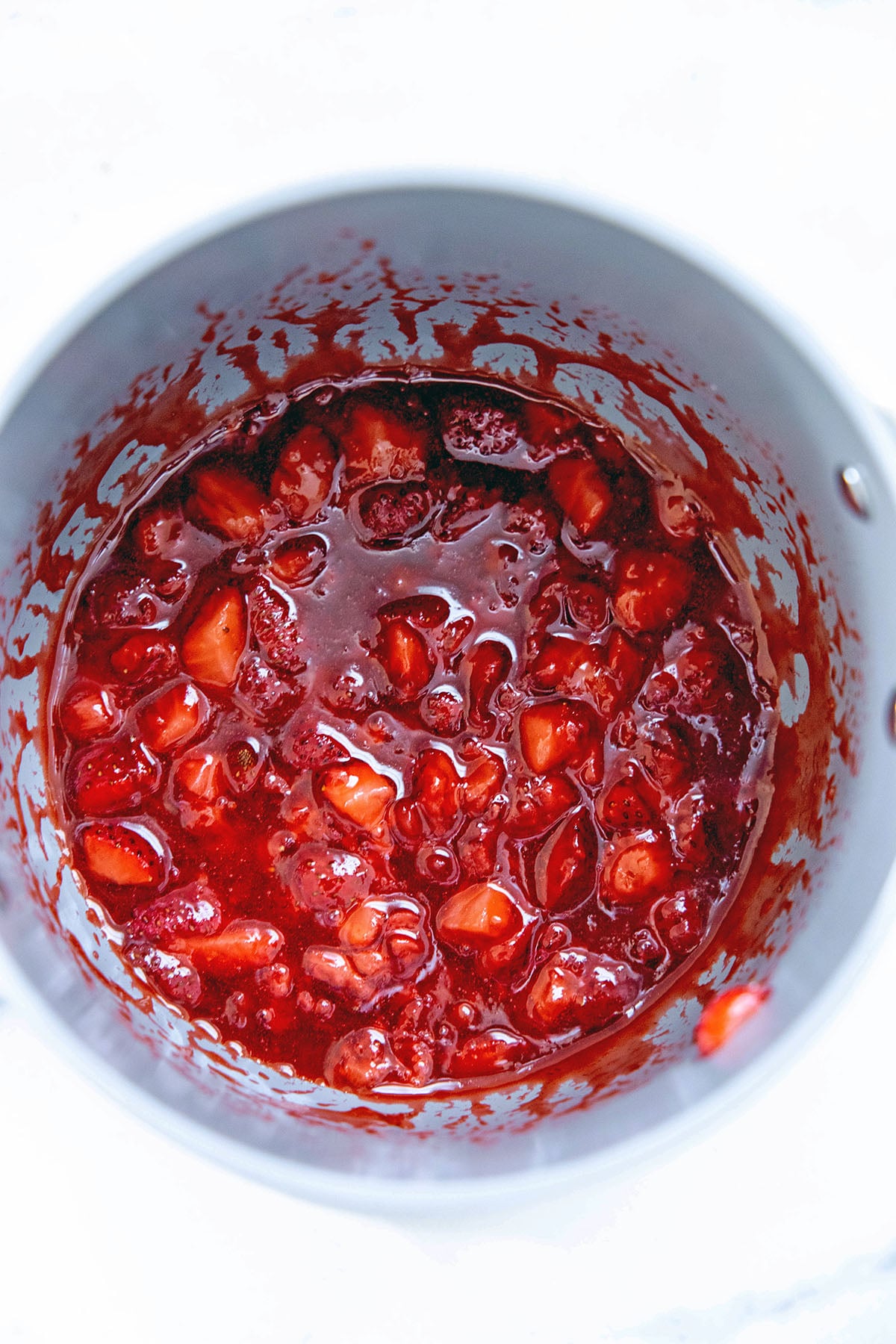 Jammy strawberry puree in saucepan.