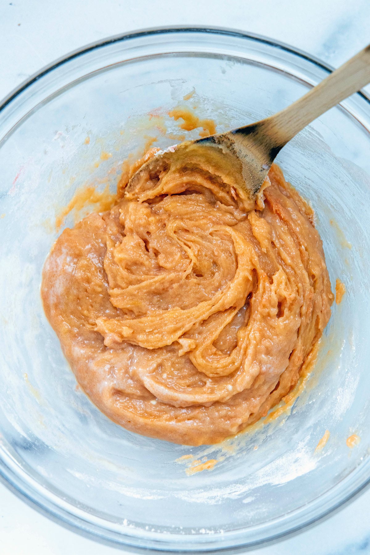 Strawberry brownie batter in a bowl with wooden spoon.