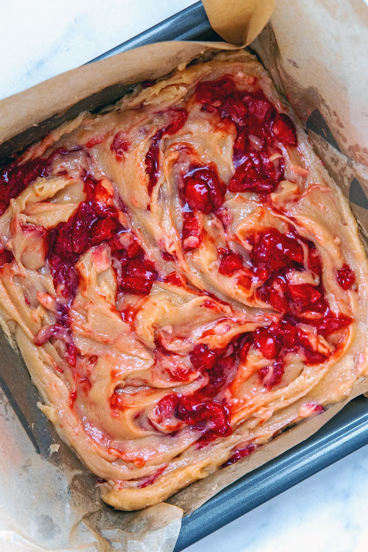Strawberry batter and jam swirled together in baking pan.
