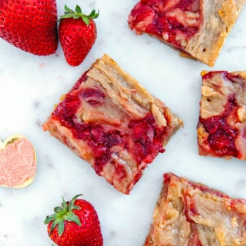 Closeup view of a strawberry brownie with strawberries and more brownies all around.