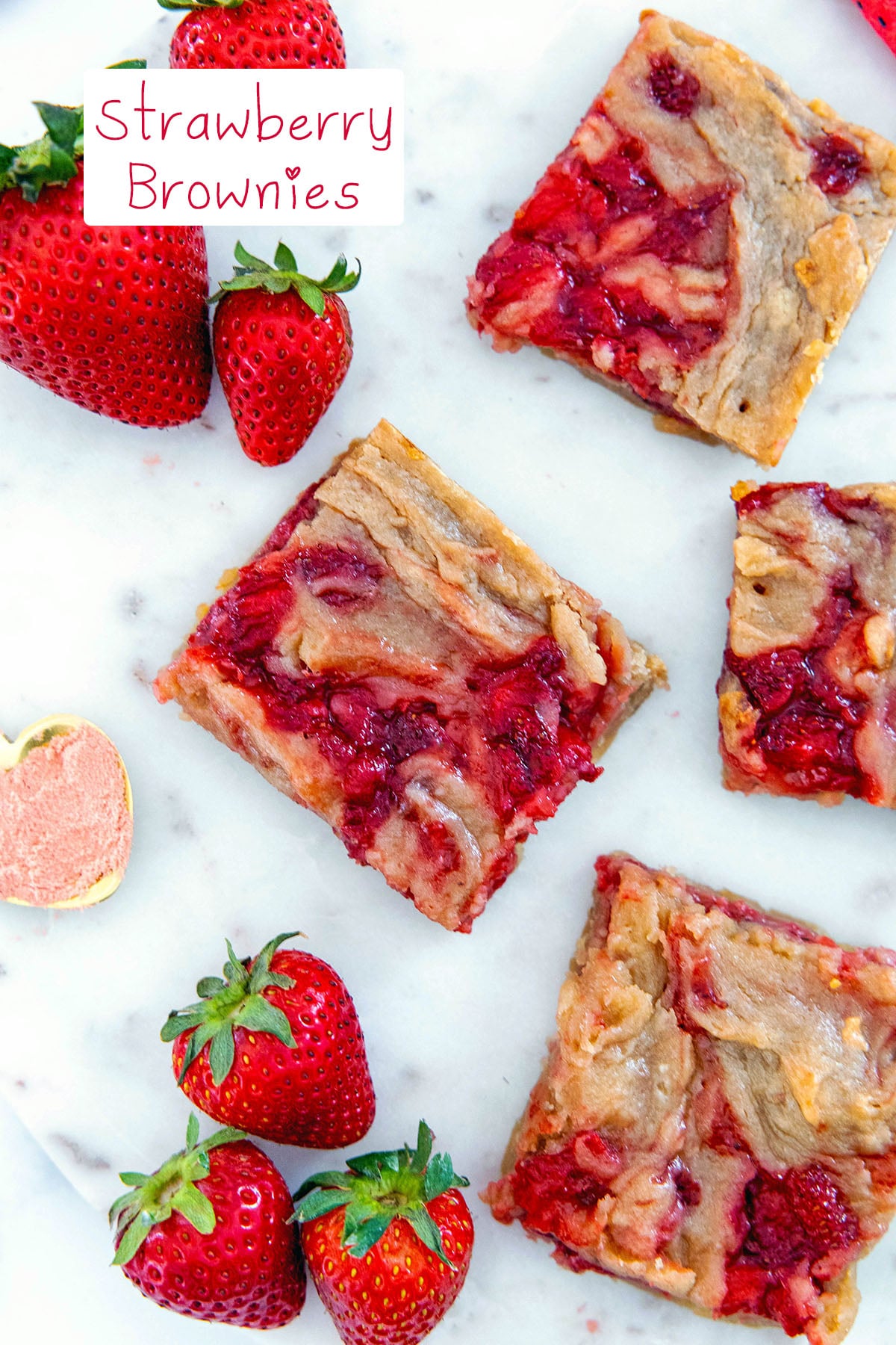 Overhead view of strawberry swirl brownies on a marble platter with fresh strawberries all around and recipe title at top.