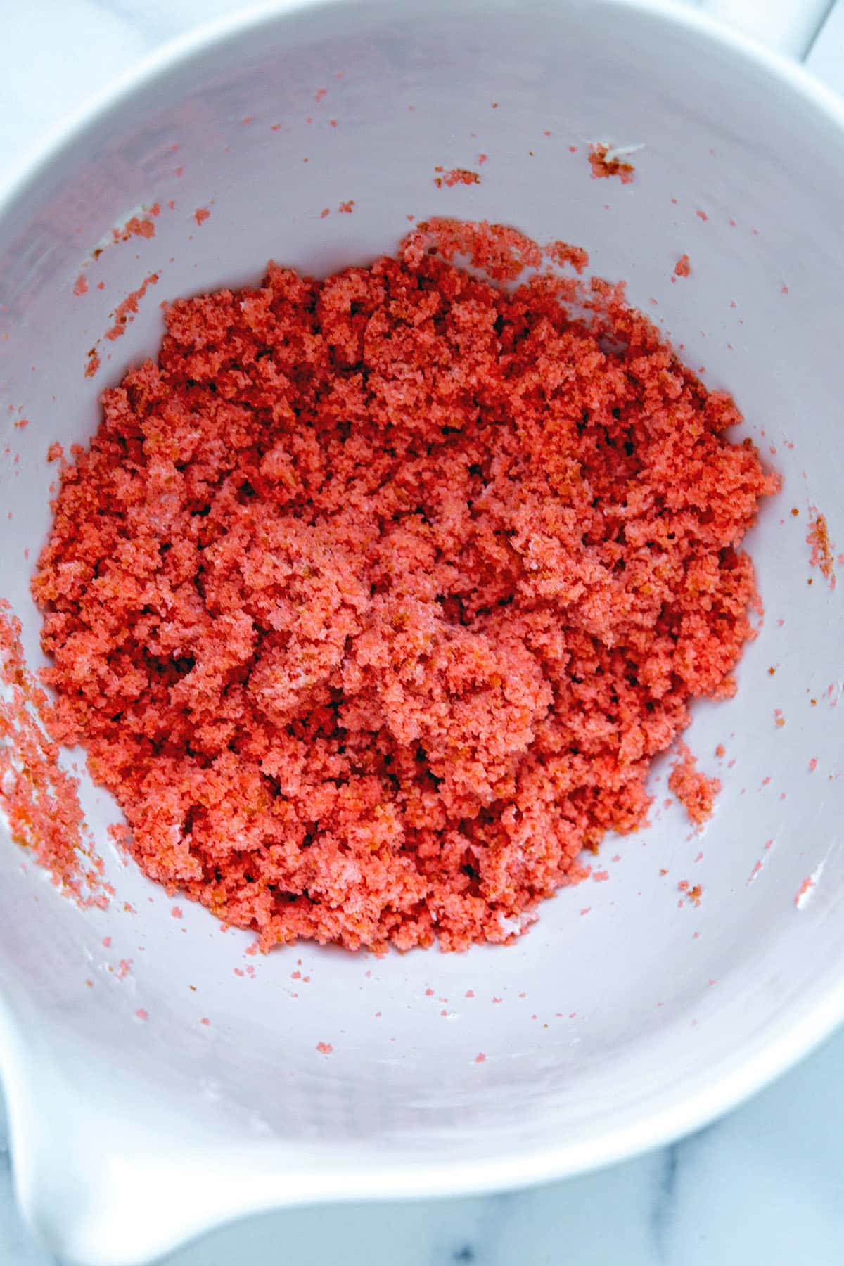 Strawberry cake and vanilla icing mixed together in mixing bowl.