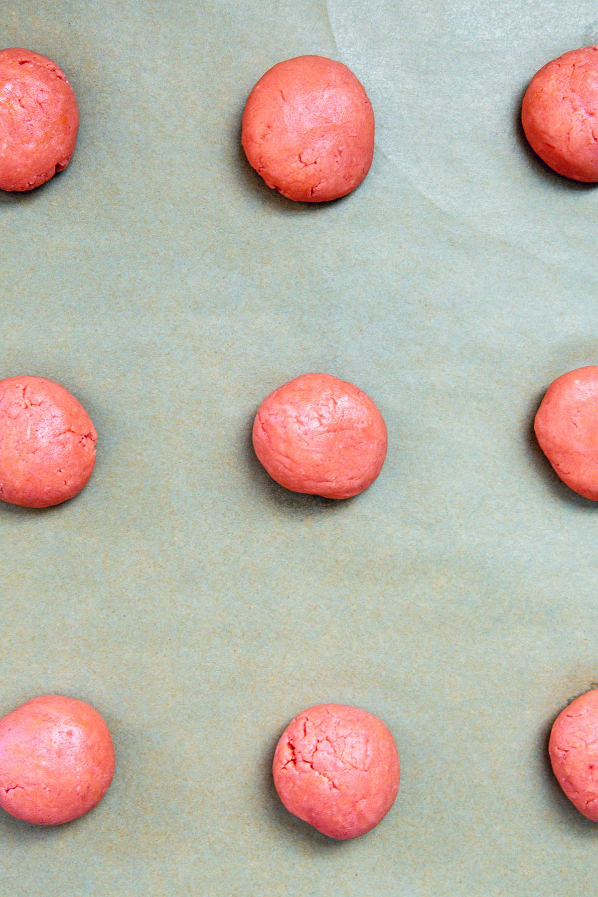 Strawberry cake mix cookie dough balls on baking sheet.