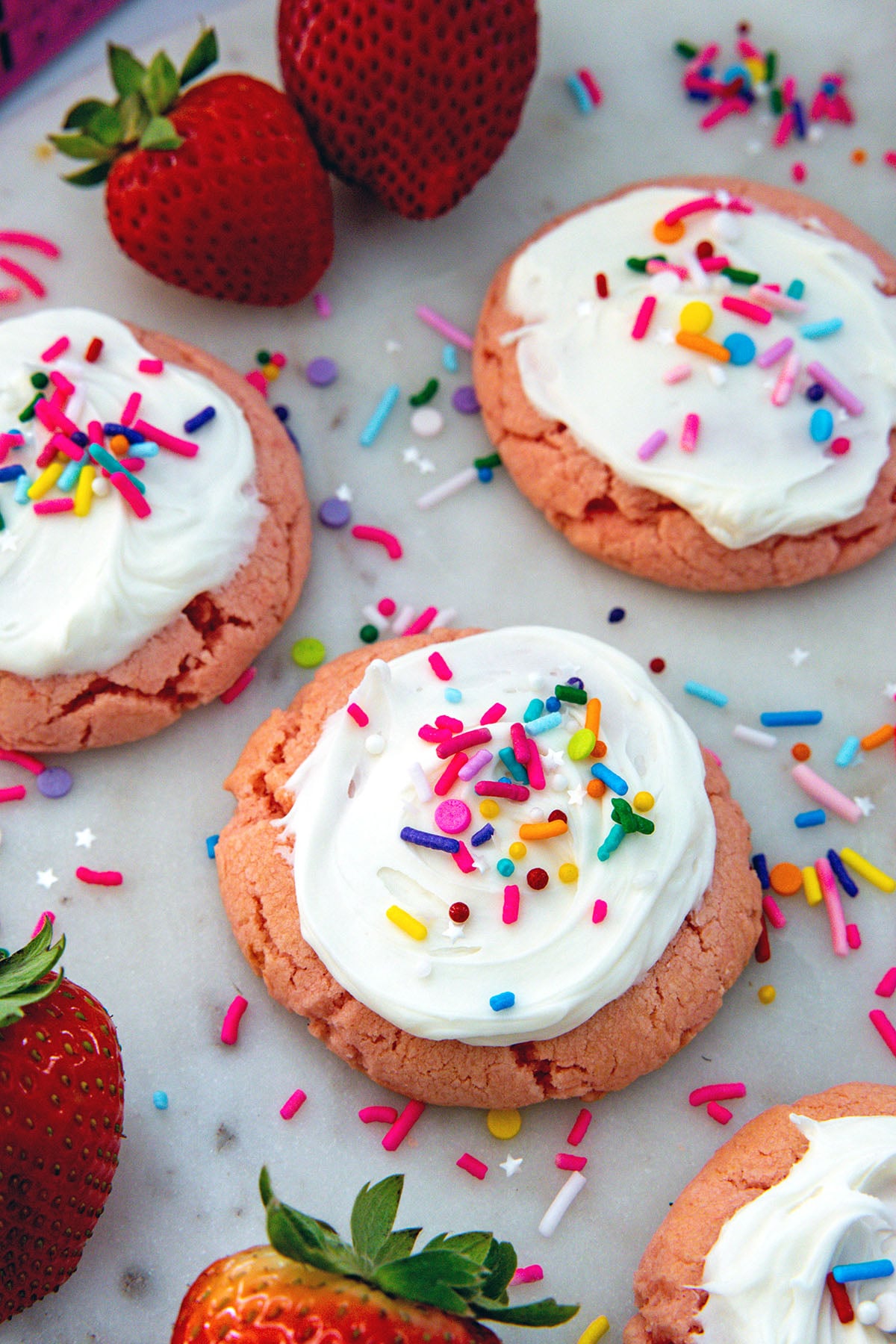 Closeup view of a frosted strawberry cookie with sprinkles.