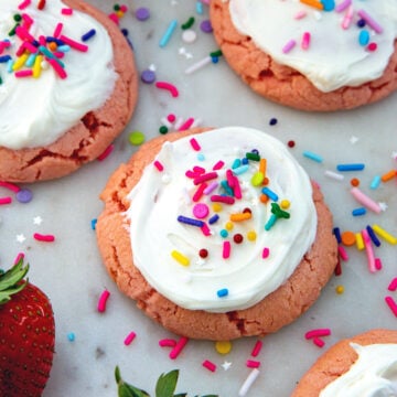 Closeup view of a strawberry cake mix cookie with icing and sprinkles.
