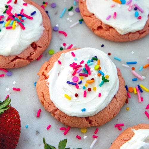 Closeup view of a strawberry cake mix cookie with icing and sprinkles.